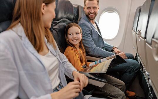 Cheerful little girl traveling with parents on airplane