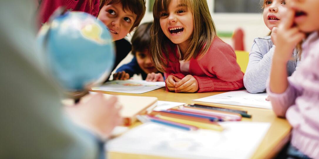 Preschool teacher and children using globe.