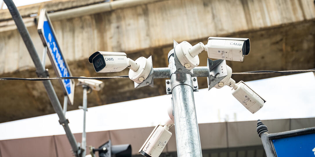 Close-up of a security street surveillance cameras on a pole under concrete Skytrain lines. Urban safety of citizens in the city