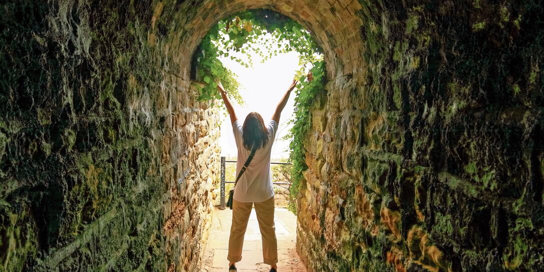 Silhouette of a lady with raised hands at the end of a tunnel