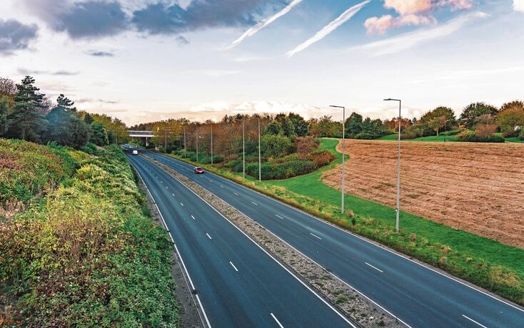 Road with car traffic crossing beautiful country land
