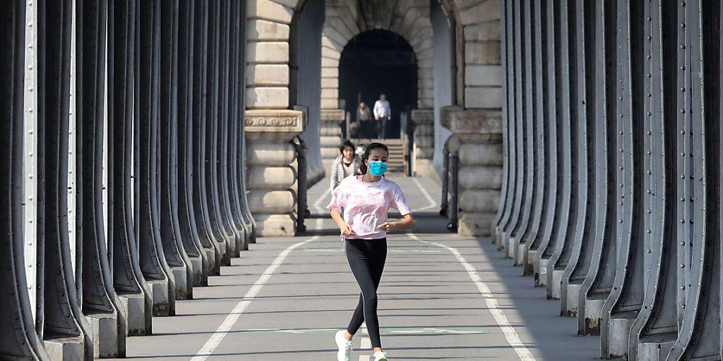 Eine Frau, die eine Schutzmaske trägt, während sie am zwölften Tag einer coronabedingten Abriegelung in Paris joggt. Seit Freitagmorgen (28. August) müssen die Menschen überall in Paris aufgrund er Corona-Pandemie unter freiem Himmel eine Maske tragen. Foto: Ludovic Marin/AFP/dpa Eine Frau, die eine Schutzmaske trägt, während sie am zwölften Tag einer coronabedingten Abriegelung in Paris joggt. Seit Freitagmorgen (28. August) müssen die Menschen überall in Paris aufgrund er Corona-Pandemie unter freiem Himmel eine Maske tragen. Foto: Ludovic Marin/AFP/dpa