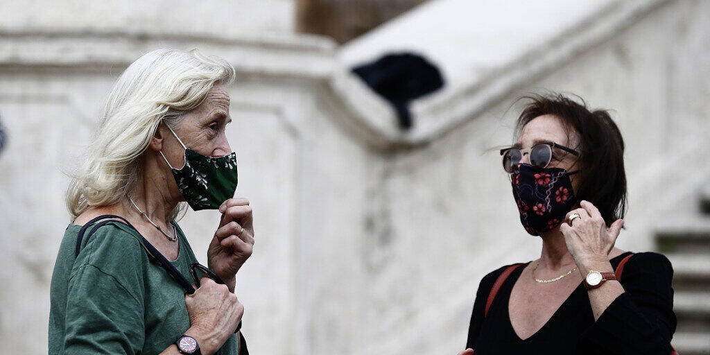 ARCHIV - Menschen mit Mund-Nasen-Schutz stehen vor einer Treppe in Rom. Angesichts landesweit steigender Zahlen von Corona-Neuinfektion führt Italien eine Maskenpflicht im Freien ein. Foto: Cecilia Fabiano/LaPresse via ZUMA Press/dpa