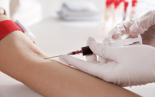Nurse drawing blood sample from patient in clinic, closeup