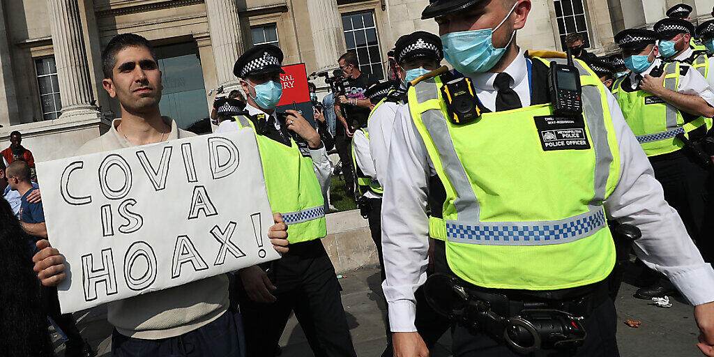 Ein Mann hält am Trafalgar Square bei einer Demonstration von Impfgegnern ein Schild mit der Aufschrift "Covid is a hoax" (Covid ist ein Schwindel) in die Höhe. Foto: Yui Mok/PA Wire/dpa Ein Mann hält am Trafalgar Square bei einer Demonstration von Impfgegnern ein Schild mit der Aufschrift "Covid is a hoax" (Covid ist ein Schwindel) in die Höhe. Foto: Yui Mok/PA Wire/dpa