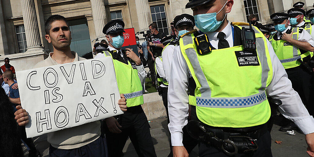 Ein Mann hält am Trafalgar Square bei einer Demonstration von Impfgegnern ein Schild mit der Aufschrift "Covid is a hoax" (Covid ist ein Schwindel) in die Höhe. Foto: Yui Mok/PA Wire/dpa