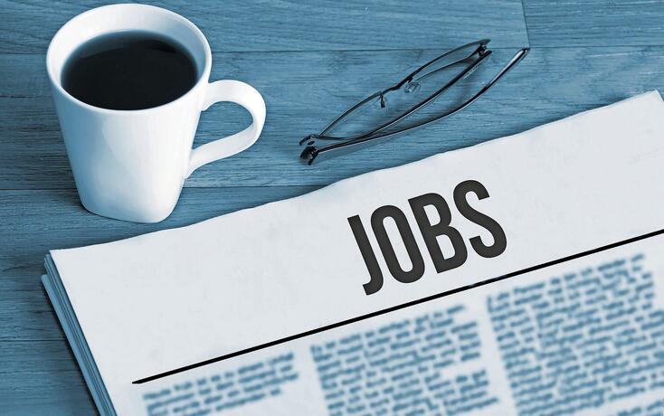 Cup of coffee, reading glasses and a newspaper with job advertisements during a job search