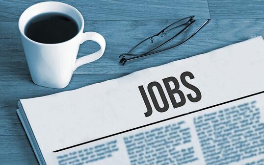 Cup of coffee, reading glasses and a newspaper with job advertisements during a job search