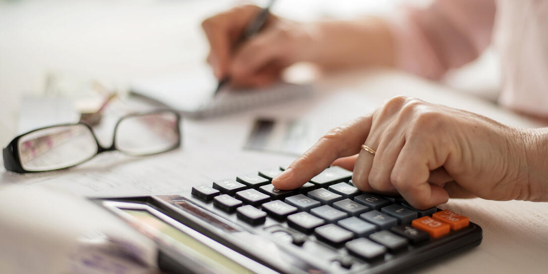 Pension calculation concept, old hands counting finances on a home calculator , close- up Pension calculation concept, old hands counting finances on a home calculator , close- up