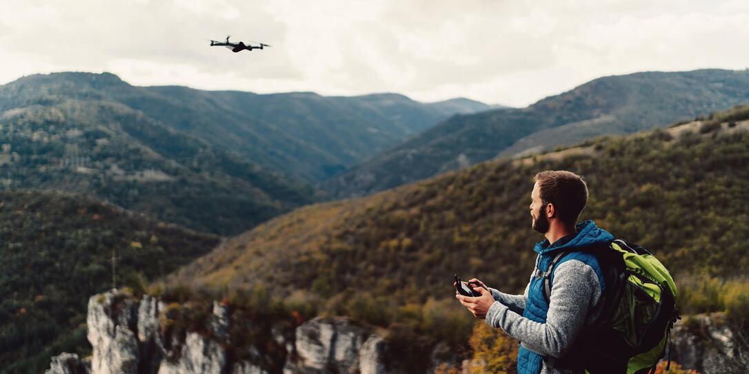 Hiker on the mountain top flying a drone to make videos and photos