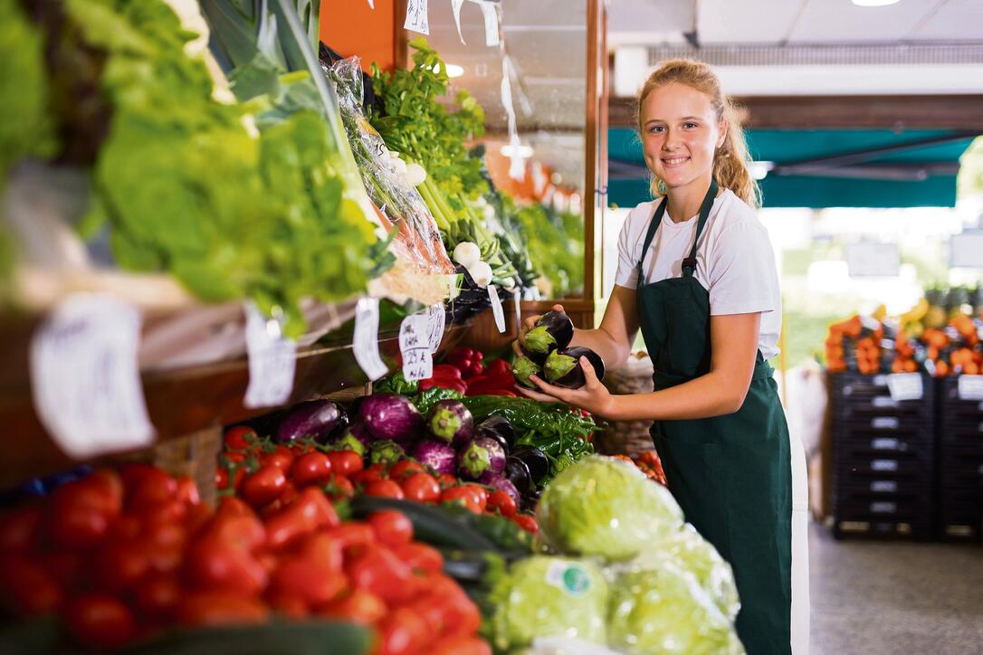 Young girl who works part-time as a trainee saleswoman puts on the showcase eggplants