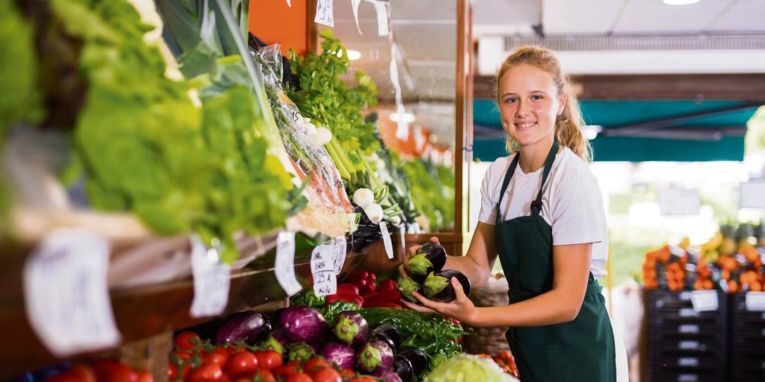 Young girl who works part-time as a trainee saleswoman puts on the showcase eggplants