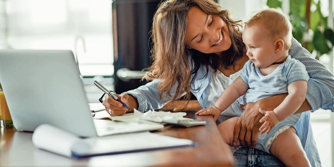 Happy mother talking to her baby while working at home.