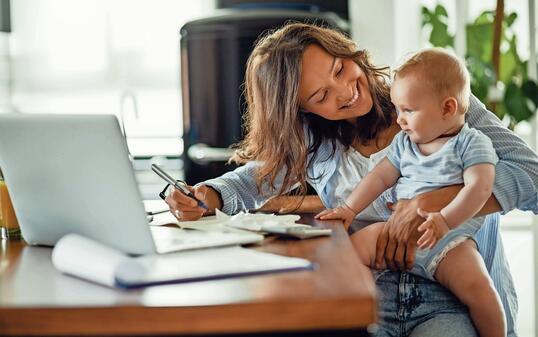 Happy mother talking to her baby while working at home.