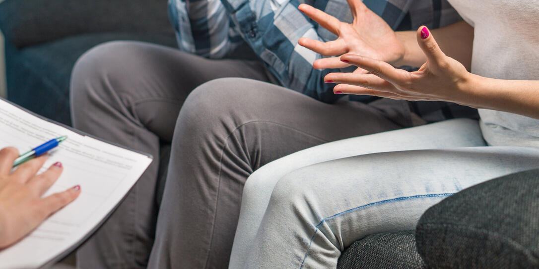 Couple having fight in therapy or marriage counseling. Man and woman sitting on couch. Wife waving hands. Session with psychologist, counselor, therapist, psychiatrist or relationship consultant.