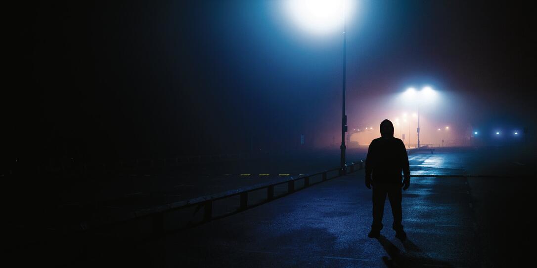 Sinister silhouette man lurking in deserted parking lot