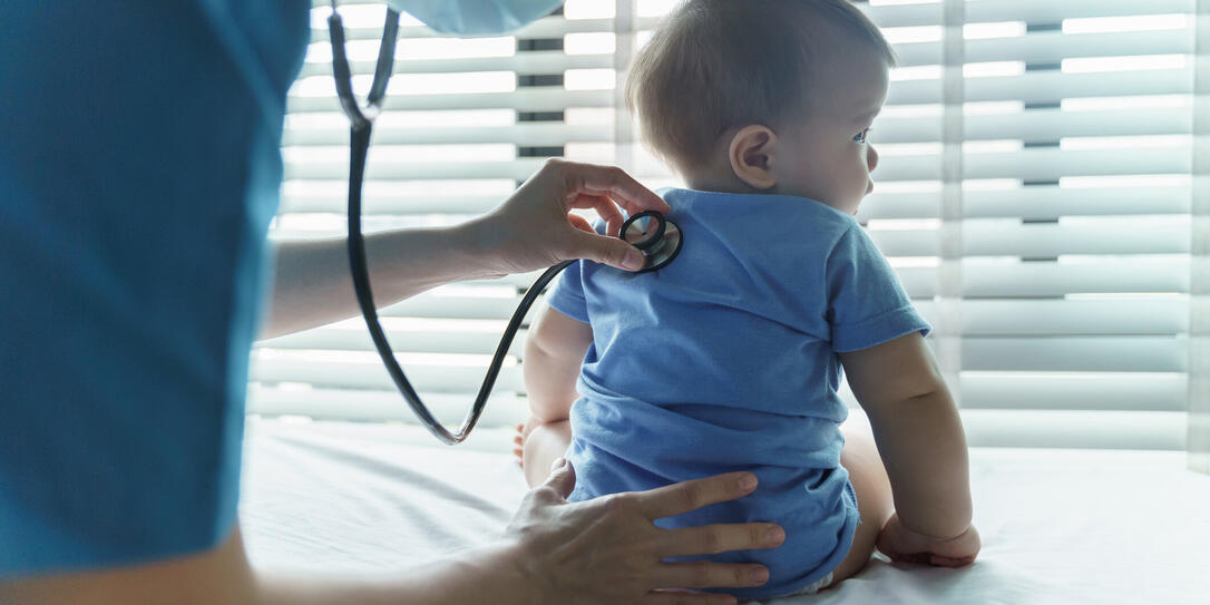 Asian female Pediatrician doctor examining her little baby patient with stethoscope in medical room
