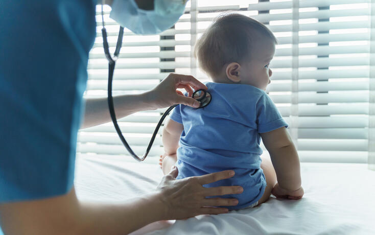 Asian female Pediatrician doctor examining her little baby patient with stethoscope in medical room