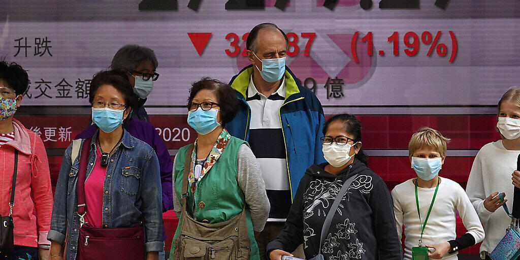 Die Furcht vor dem Coronavirus kommt nun immer stärker an den Börsen an - im Bild Passanten vor der Hong Kong Stock Exchange. (Archiv)