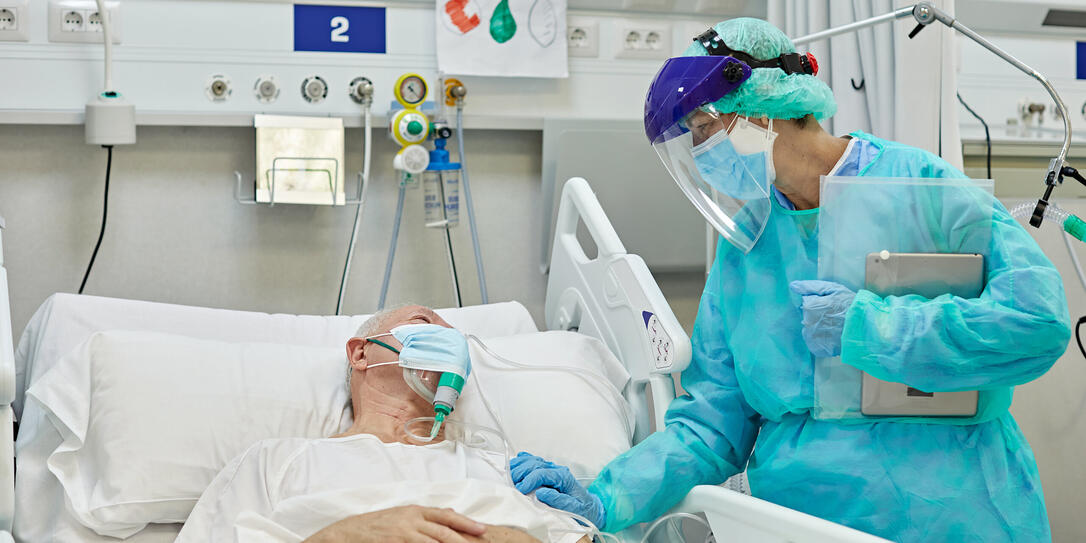 Female Doctor Supporting Male Patient Lying in Hospital Bed Female Doctor Supporting Male Patient Lying in Hospital Bed