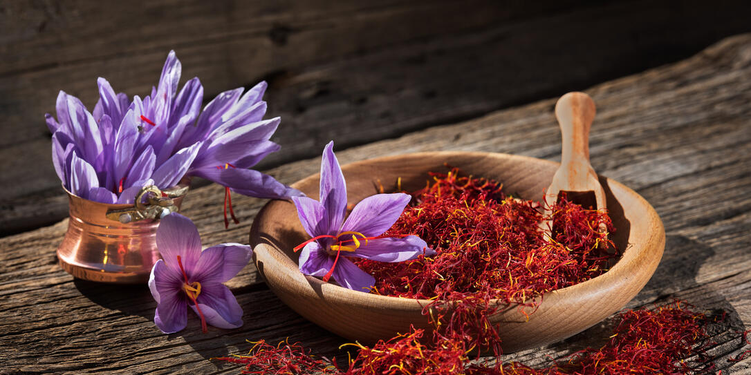 Saffron in wooden bowl on wooden table with saffron flowers on the side Saffron in wooden bowl on wooden table with saffron flowers on the side