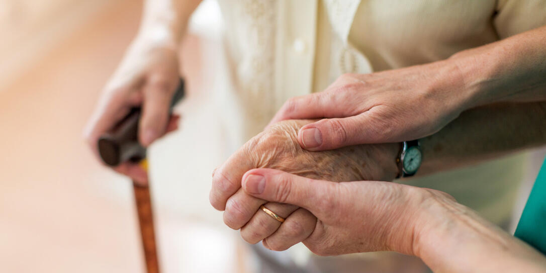 Nurse consoling her elderly patient by holding her hands