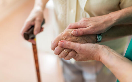 Nurse consoling her elderly patient by holding her hands