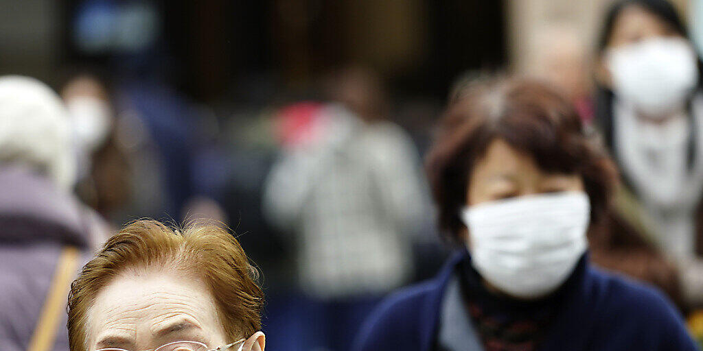 Menschen tragen Gesichtsmasken in einem Einkaufsviertel in Tokio. (Archivbild) Menschen tragen Gesichtsmasken in einem Einkaufsviertel in Tokio. (Archivbild)