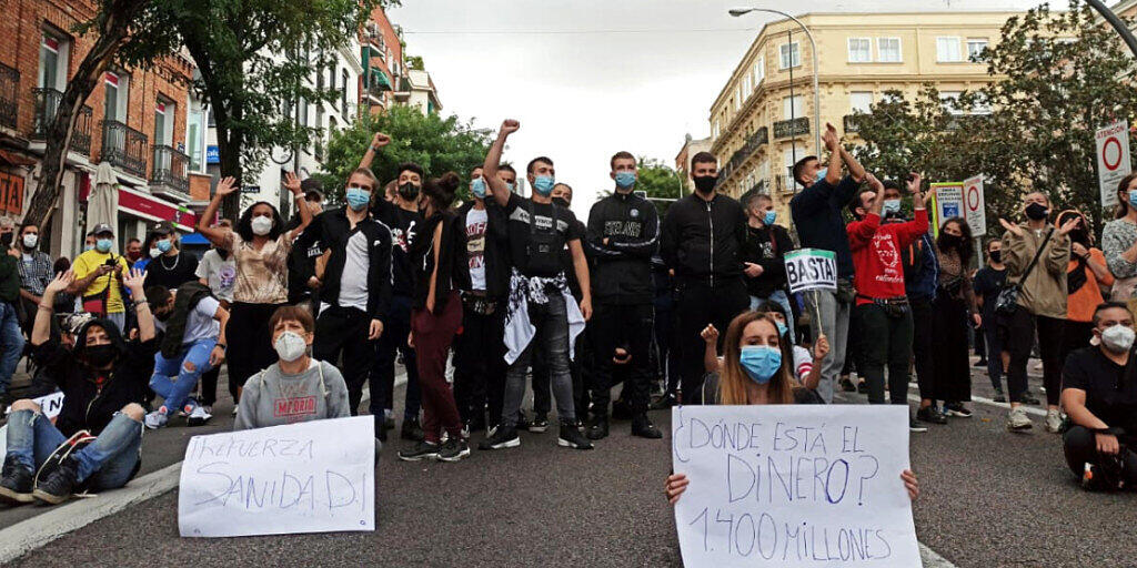 Demonstranten sitzen auf einer Strasse im Stadtbezirk Villa de Vallecas. Tausende Menschen haben in Madrid gegen die Abriegelungen von mehreren einkommensschwachen Gebieten der spanischen Hauptstadt zur Eindämmung der Corona-Pandemie protestiert. Foto: David Obach/EUROPA PRESS/dpa Demonstranten sitzen auf einer Strasse im Stadtbezirk Villa de Vallecas. Tausende Menschen haben in Madrid gegen die Abriegelungen von mehreren einkommensschwachen Gebieten der spanischen Hauptstadt zur Eindämmung der Corona-Pandemie protestiert. Foto: David Obach/EUROPA PRESS/dpa