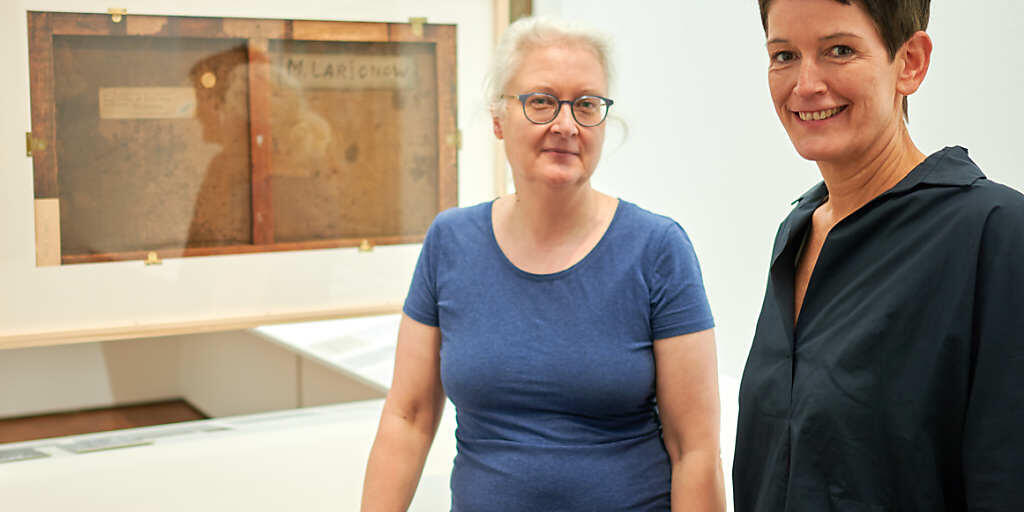 Petra Mandt (l), Restauratorin, und Rita Kersting, stellvertretende Direktorin, stehen bei einer Vorbesichtigung der Ausstellung "Russische Avantgarde im Museum Ludwig - Original und Fälschung Fragen, Untersuchungen, Erklärungen" vor der Rückseite eines Bildes des Malers M. F. Larionow. Foto: Henning Kaiser/dpa