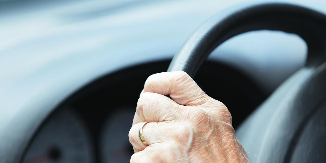 Hand of Senior Man Driver on Car Steering Wheel