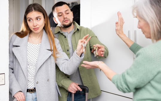 Dissatisfied owner receiving keys from married couple tenants