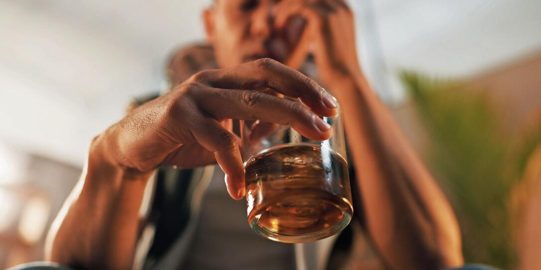 Alcoholic, stress and glass of whiskey with person in living room for substance abuse, risk and depression. Mental health, wine and liquor with drink at home for temptation, withdrawal and control