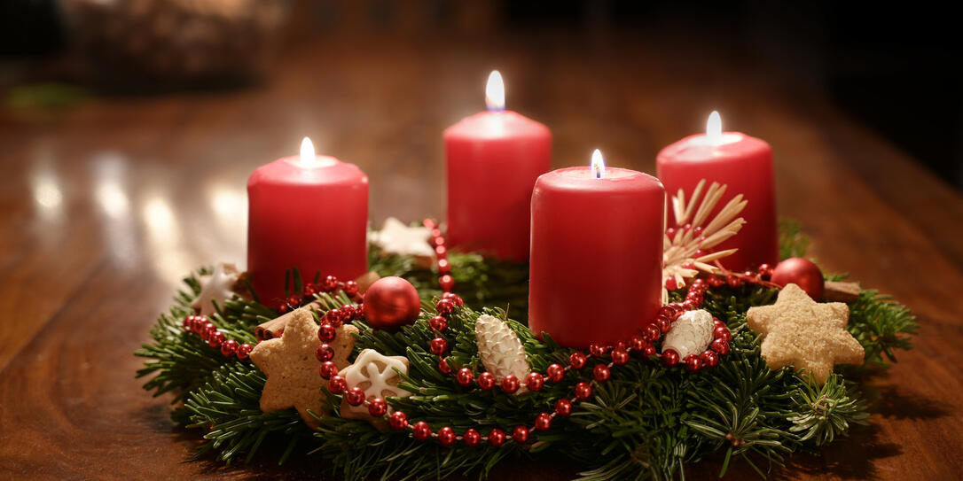 Fourth Advent - decorated Advent wreath from fir branches with red burning candles on a wooden table in the time before Christmas, festive bokeh in the warm dark background, copy space, selected focus Fourth Advent - decorated Advent wreath from fir branches with red burning candles on a wooden table in the time before Christmas, festive bokeh in the warm dark background, copy space, selected focus