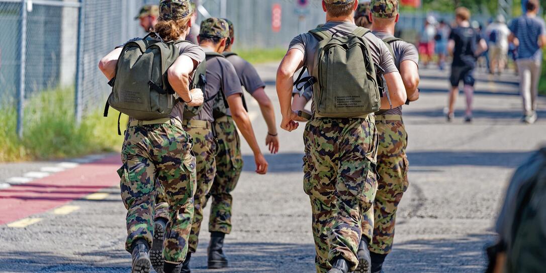 Rear view of Swiss Army soldiers walking at Swiss town.