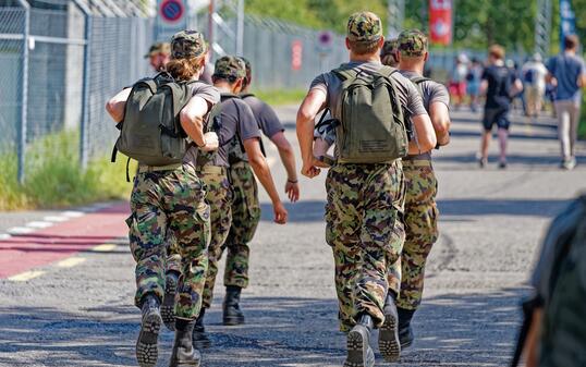 Rear view of Swiss Army soldiers walking at Swiss town.