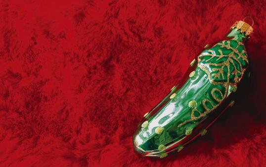 Christmas pickle ornament on stocking material background