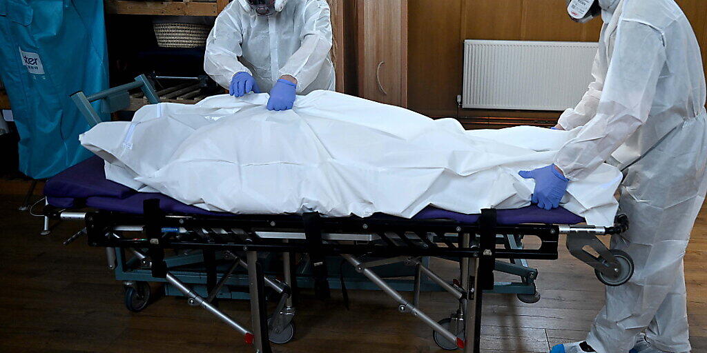 Bestatter in London kümmern sich in Schutzkleidern um ein Corona-Todesopfer. Bestatter in London kümmern sich in Schutzkleidern um ein Corona-Todesopfer.