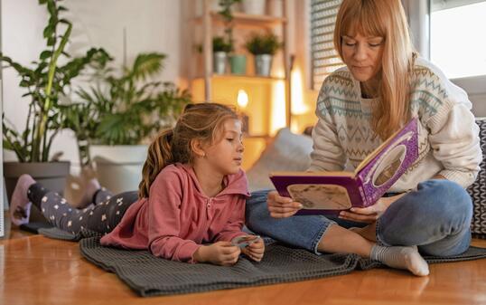 Mother and little daughter enjoying book together