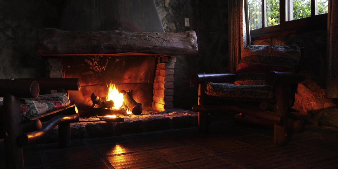 Fireplace with wooden logs, chairs and window