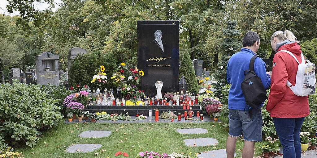 Menschen stehen am Grab des tschechischen Sängers Karel Gott auf dem Malvazinky-Friedhof, wo frische Blumen stehen und Kerzen brennen. Vor einem Jahr, am 1. Oktober 2019, war der Sänger im Alter von 80 Jahren gestorben. Foto: Michael Heitmann/dpa