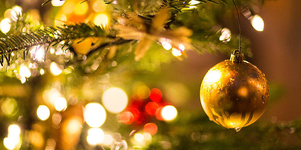 ARCHIV - Eine goldene Kugel hängt an einem Weihnachtsbaum. Foto: Friso Gentsch/dpa