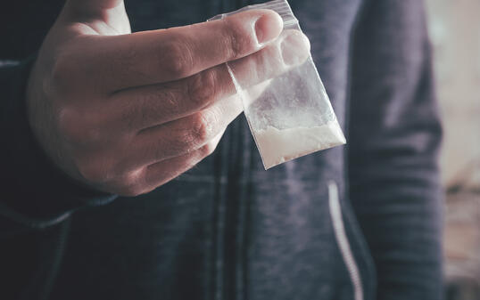 Dealing Drugs By A Man Holding A Little Bag With White Powder In His Hand