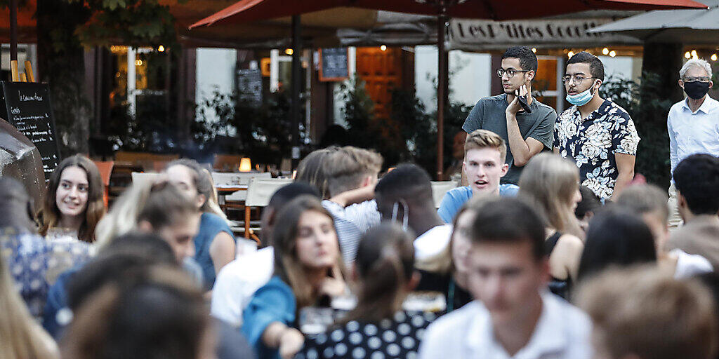 Jugendliche sitzen an Tischen auf der Terrasse eines Cafés. Angesichts steigender Corona-Zahlen hat Frankreichs Premierminister Castex an das Verantwortungsbewusstsein seiner Landsleute appelliert und warnte vor der wachsenden Ausbreitung des Virus im Land. Foto: Jean-Francois Badias/AP/dpa