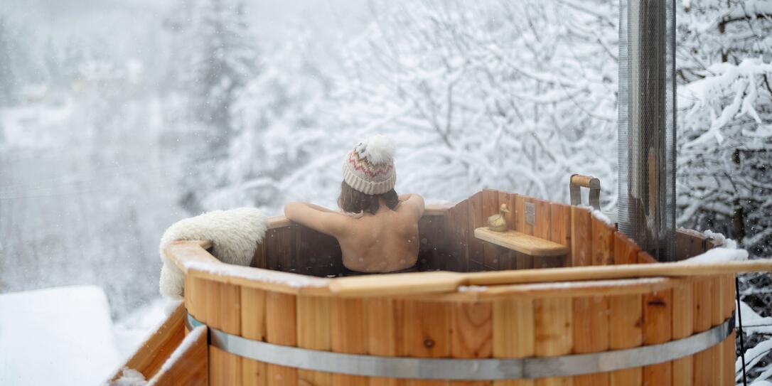 Woman relaxing in hot bath at snowy mountains