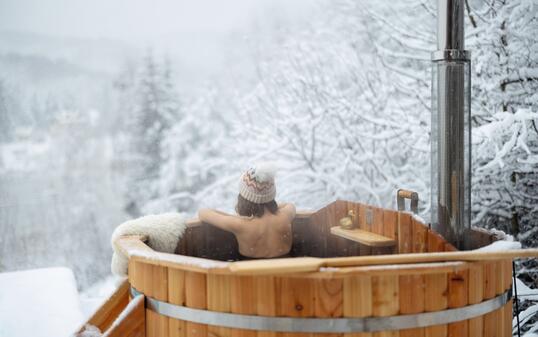 Woman relaxing in hot bath at snowy mountains
