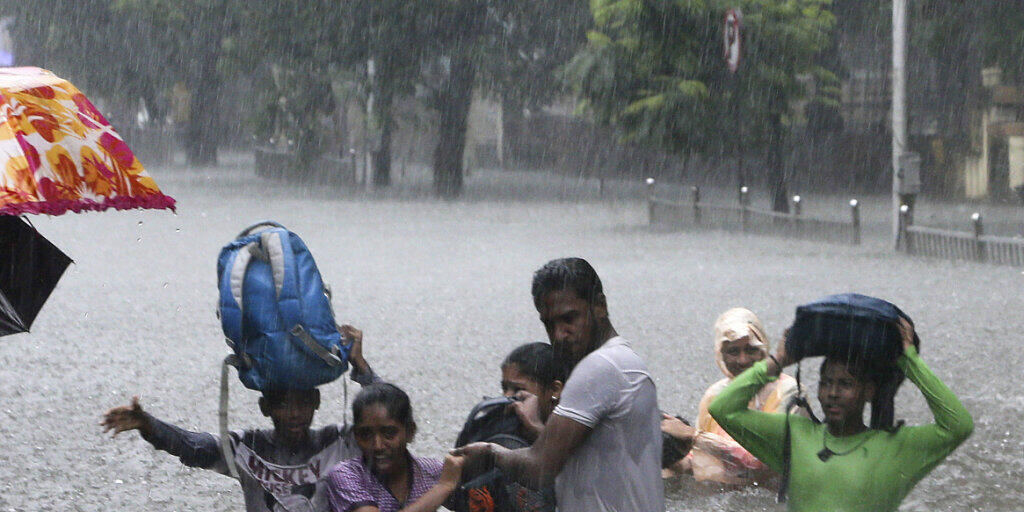 Menschen auf einer überfluteten Strasse in der indischen Metropole Mumbai. (Archivbild)