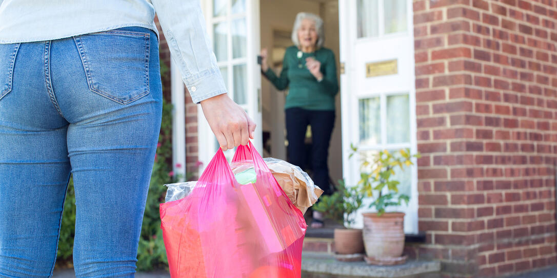 Close Up Of Woman Doing Shopping For Senior Neighbor