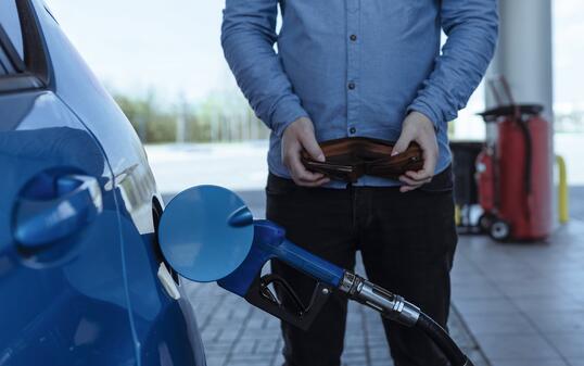refueling a car with gasoline at a gas station. Rise in fuel prices. Crisis and lack of gasoline. A man holds an empty wallet near the car