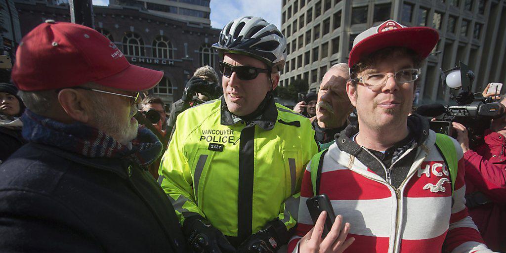Ein Polizist vermittelt zwischen Demonstranten und Anhängern Donald Trumps in Vancouver. Dort gab es Proteste gegen die Eröffnung eines neuen Trump-Hotels.